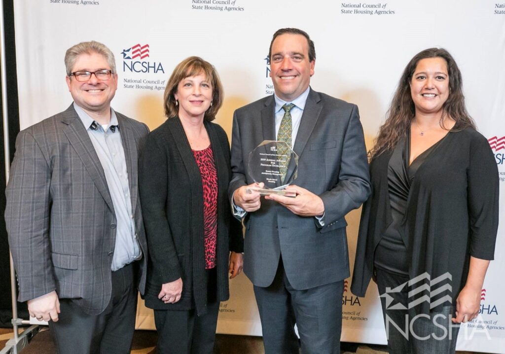 Pictured at the NCSHA Awards Ceremony: Scott Michael Dunn – of Costello Compliance, Kathleen Millerick, Michael DiChiaro and Lenore Coughlin – of RI Housing receiving NCSHA Award in Boston MA on October 21, 2019